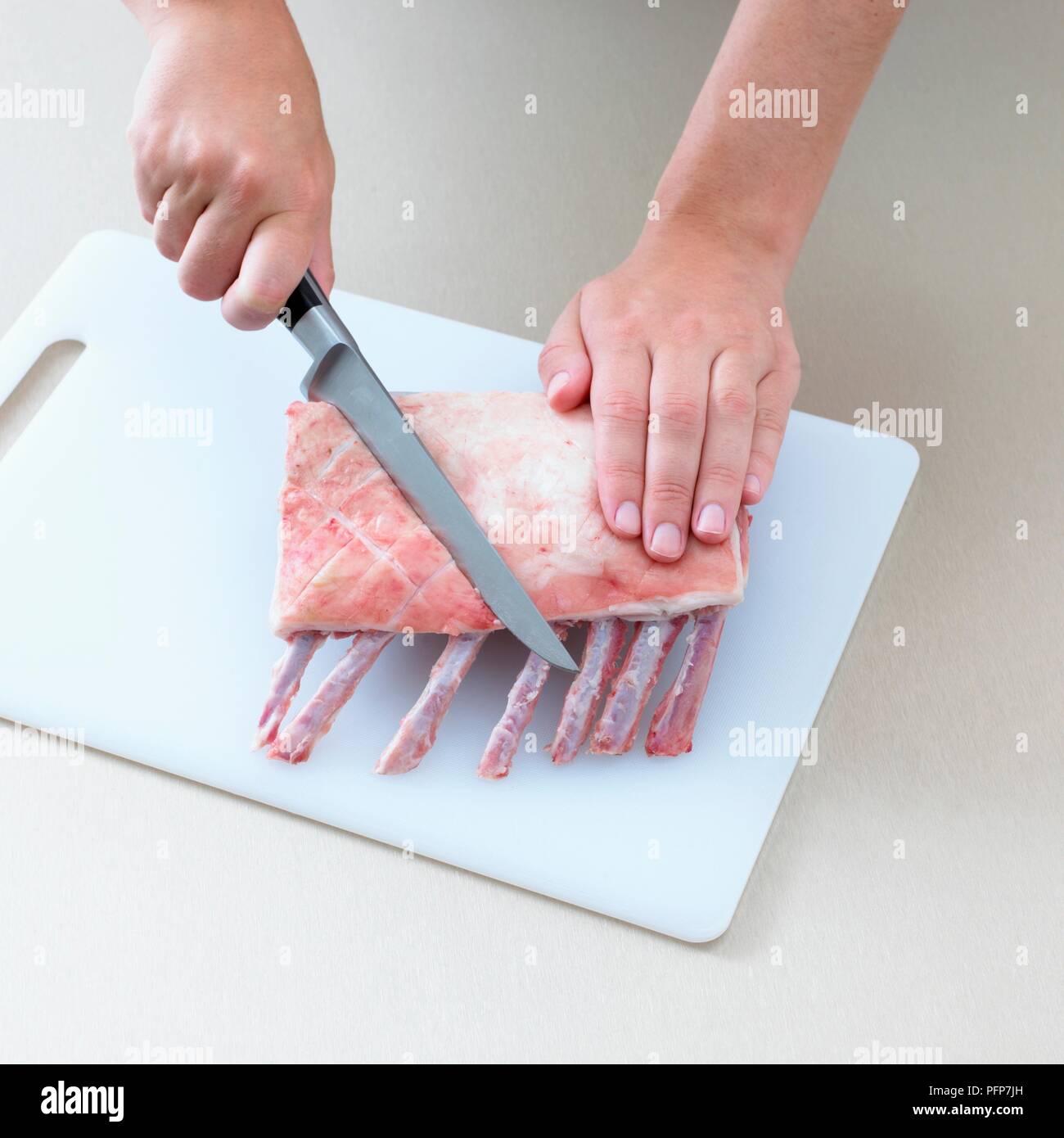 Person cutting rack of lamb, close-up Stock Photo