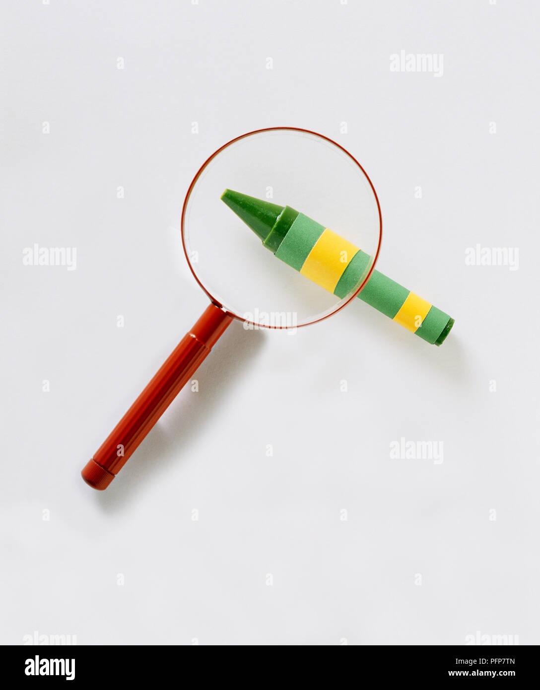 View through magnifying glass above green wax crayon Stock Photo