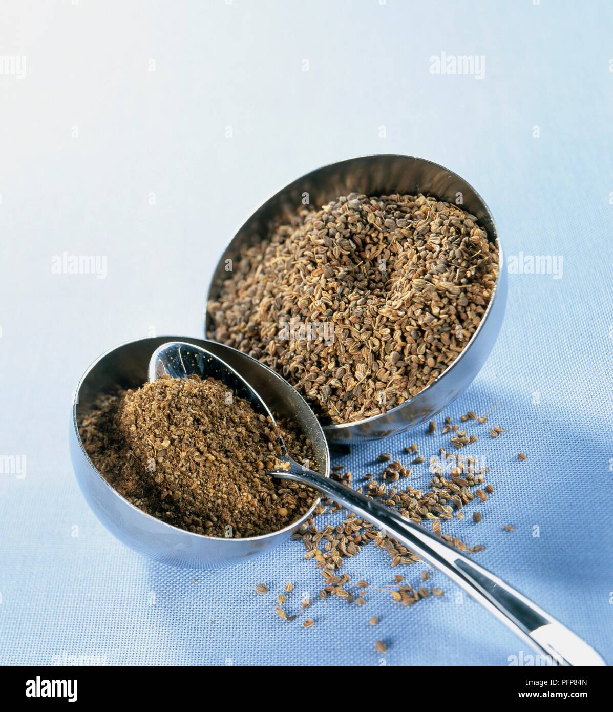 Pimpinella anisum (Aniseed), whole and ground seeds in metal bowls, with spoon Stock Photo