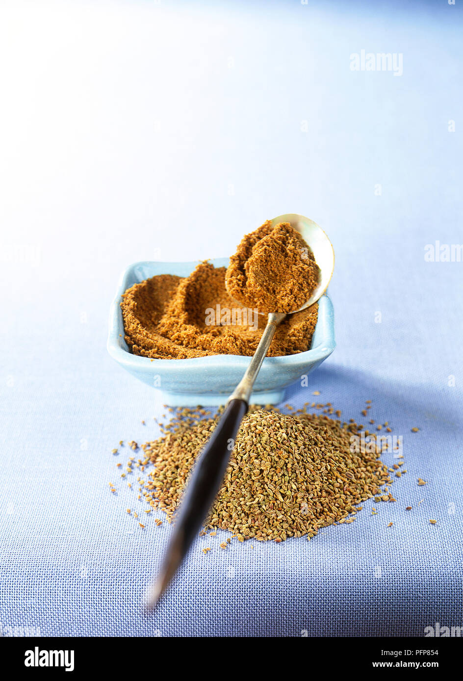 Ajowan, ground seeds in ceramic bowl and on spoon, and pile of whole