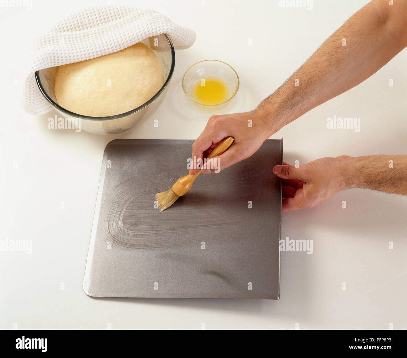 Using basting brush to cover baking sheet with melted butter Stock