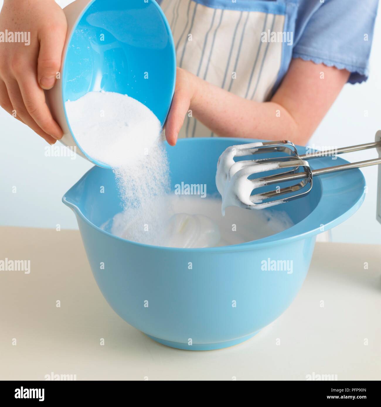 Girl pouring sugar into bowl of whisked egg whites Stock Photo Alamy