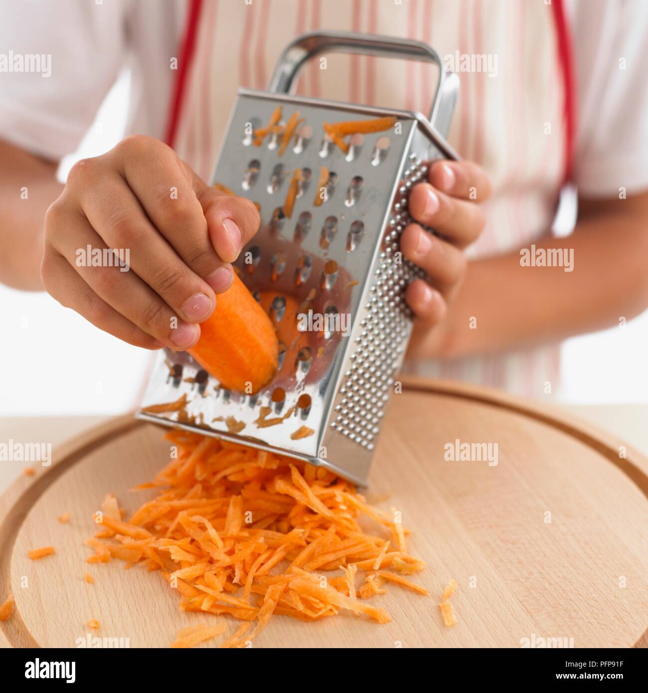 https://c8.alamy.com/comp/PFP91F/boy-using-grater-to-grate-carrot-on-chopping-board-PFP91F.jpg