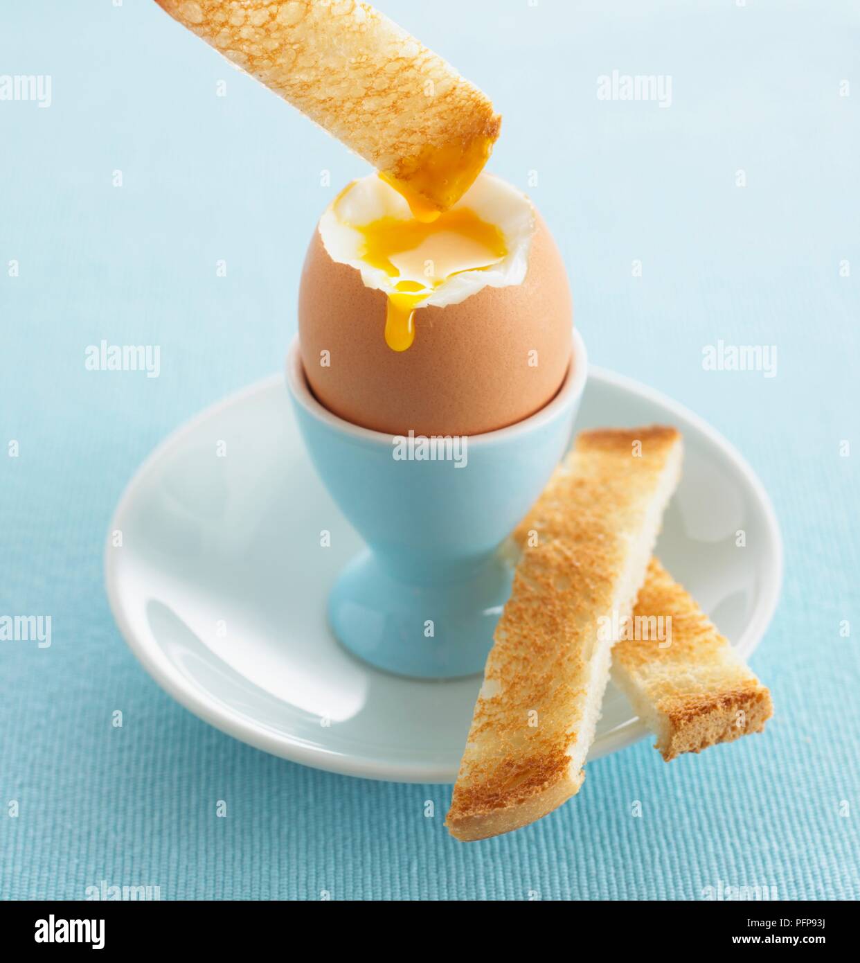 Slice of toast dipped in yolk of boiled egg Stock Photo Alamy