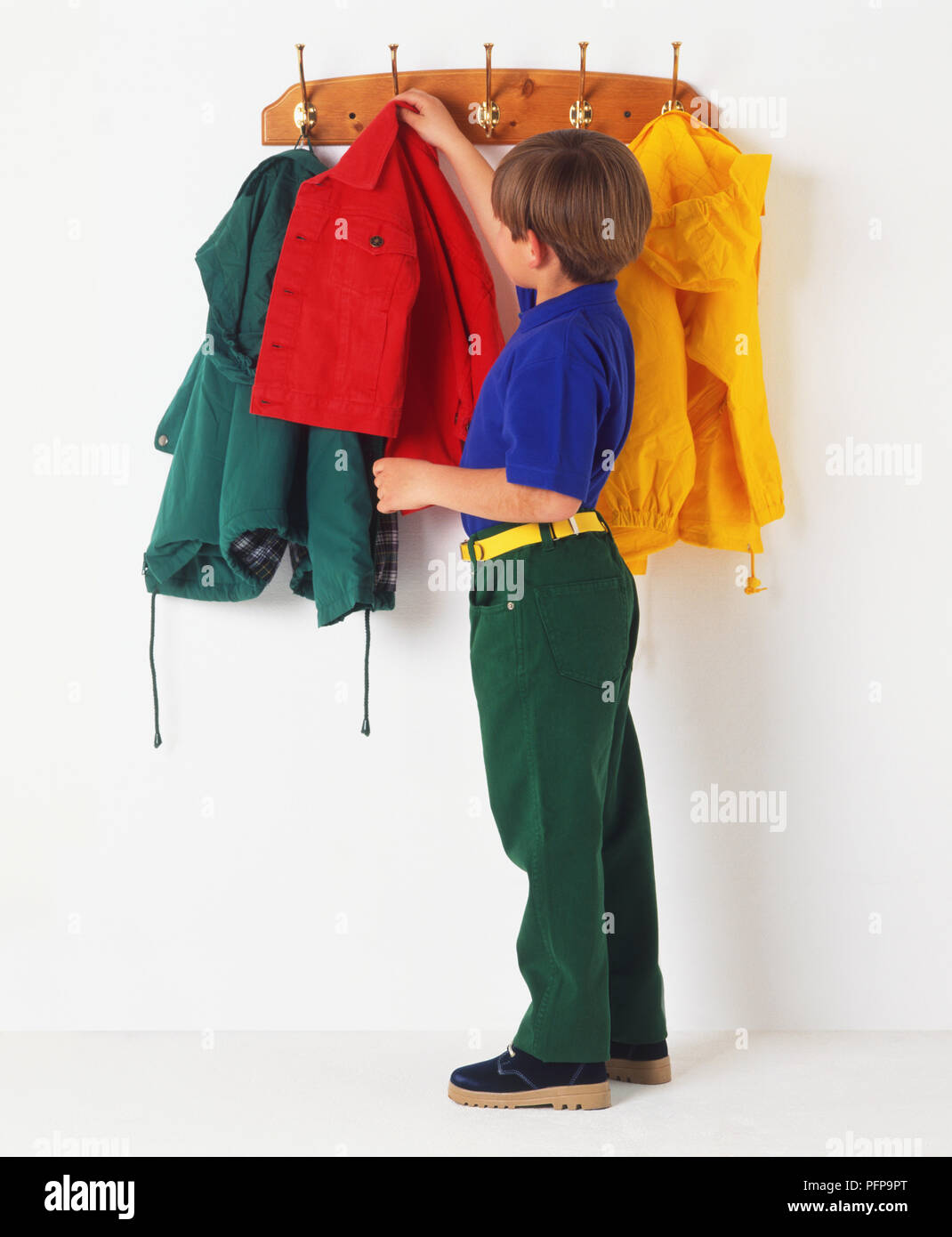 Boy hanging up a coat on a coat hook Stock Photo Alamy