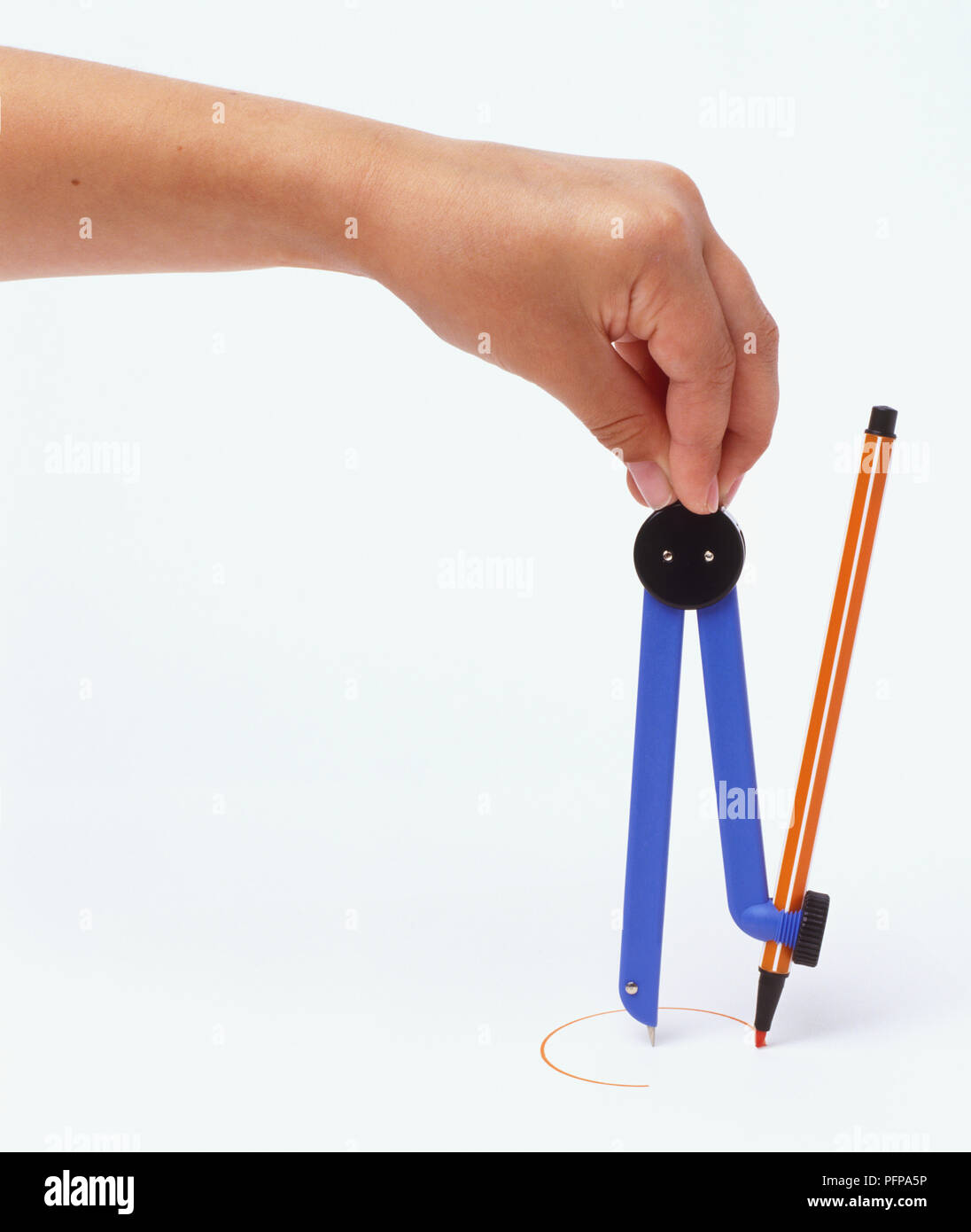 Hand holding mathematics compass, drawing circle, front view Stock