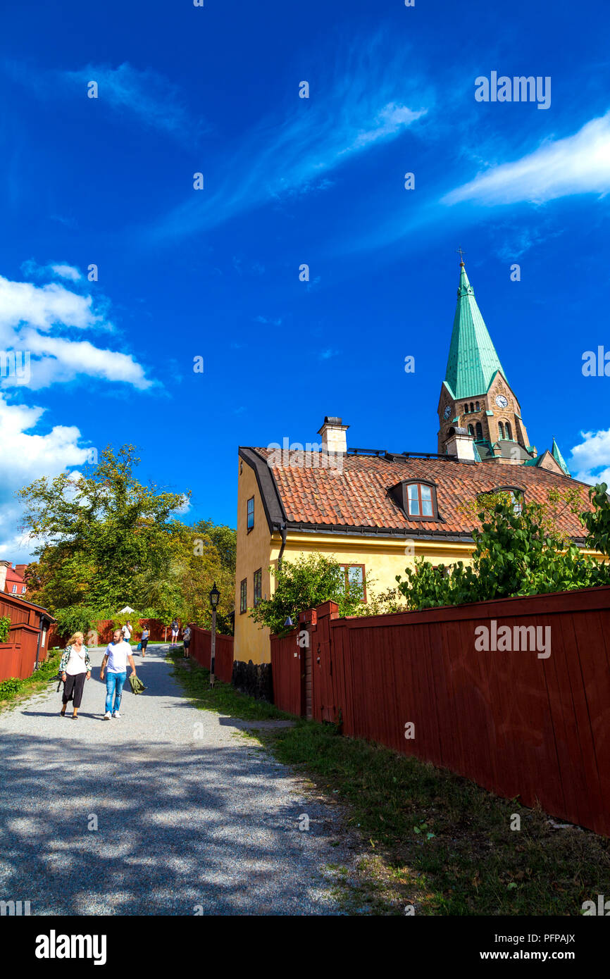 Old Swedish house and red fence with the Sofia Church in the background in Vitabergsparken, Sodermalm, Stockholm, Sweden Stock Photo