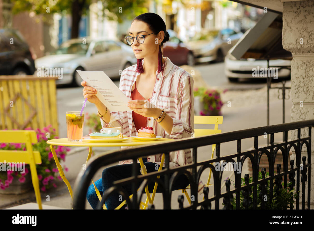 Young woman in a cafe reading a menu before eating dessert Stock Photo