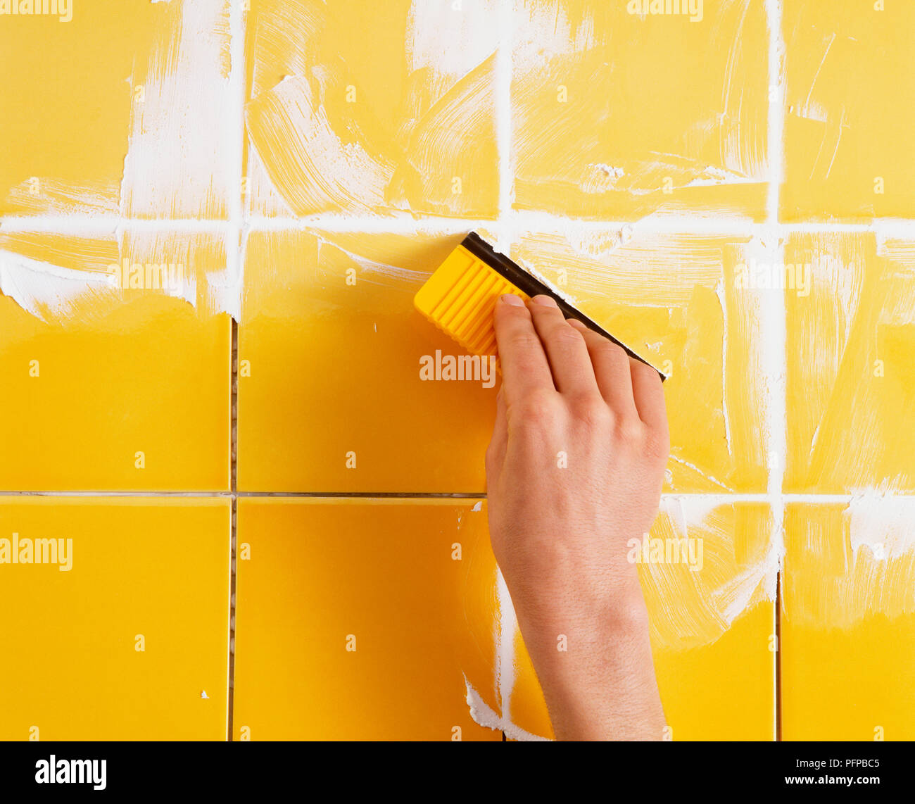Grout being applied to tiles using a grout spreader Stock Photo