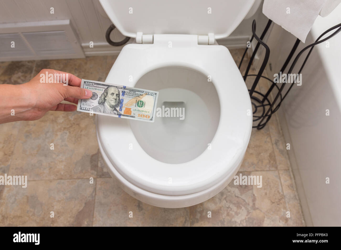 Holding crisp one hundred dollar bill into toilet; clena and bright; finance concept Stock Photo