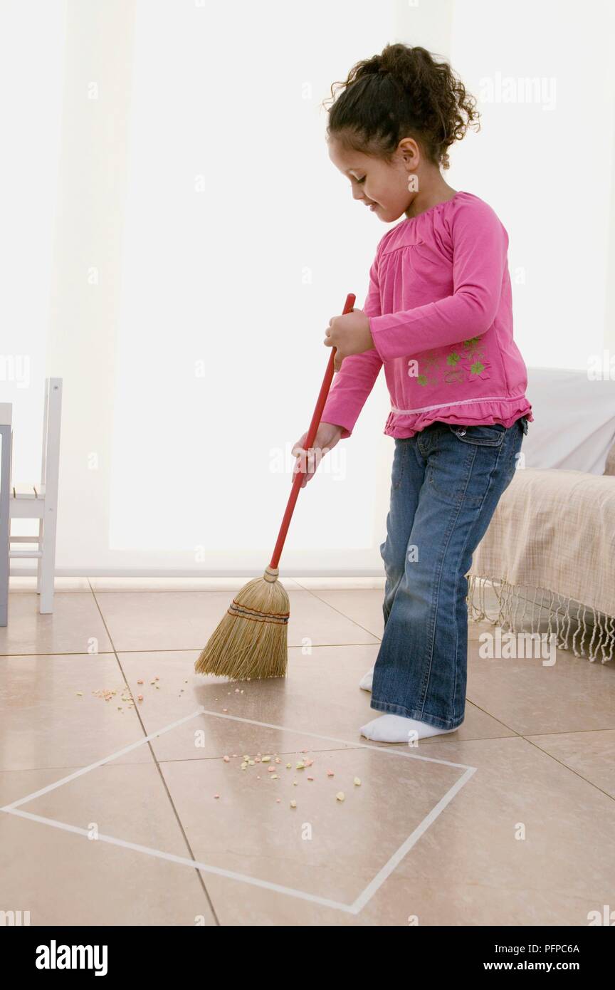 Girl using broom to sweep tiled floor, square marked out on floor Stock  Photo - Alamy
