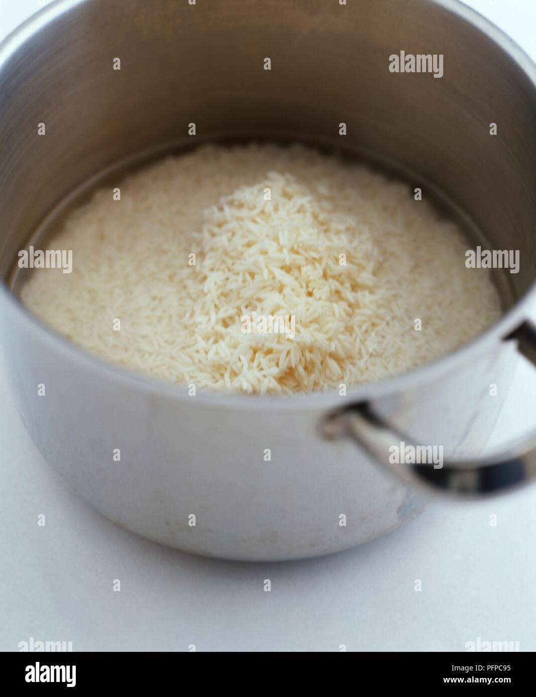 White rice in water in large saucepan Stock Photo