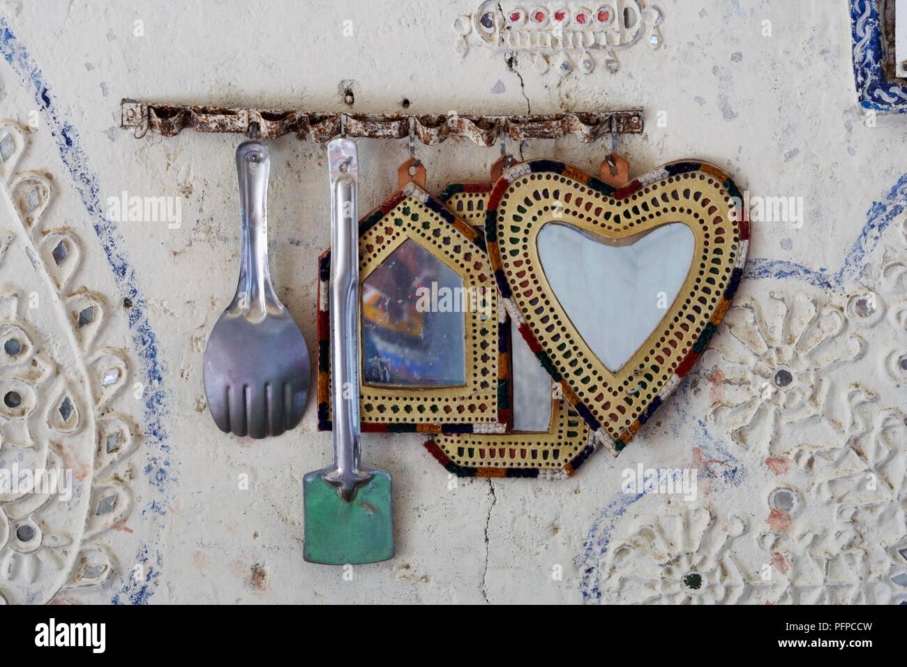 India, Gujarat, Kutch, mirrors and cooking utensils hanging on wall in