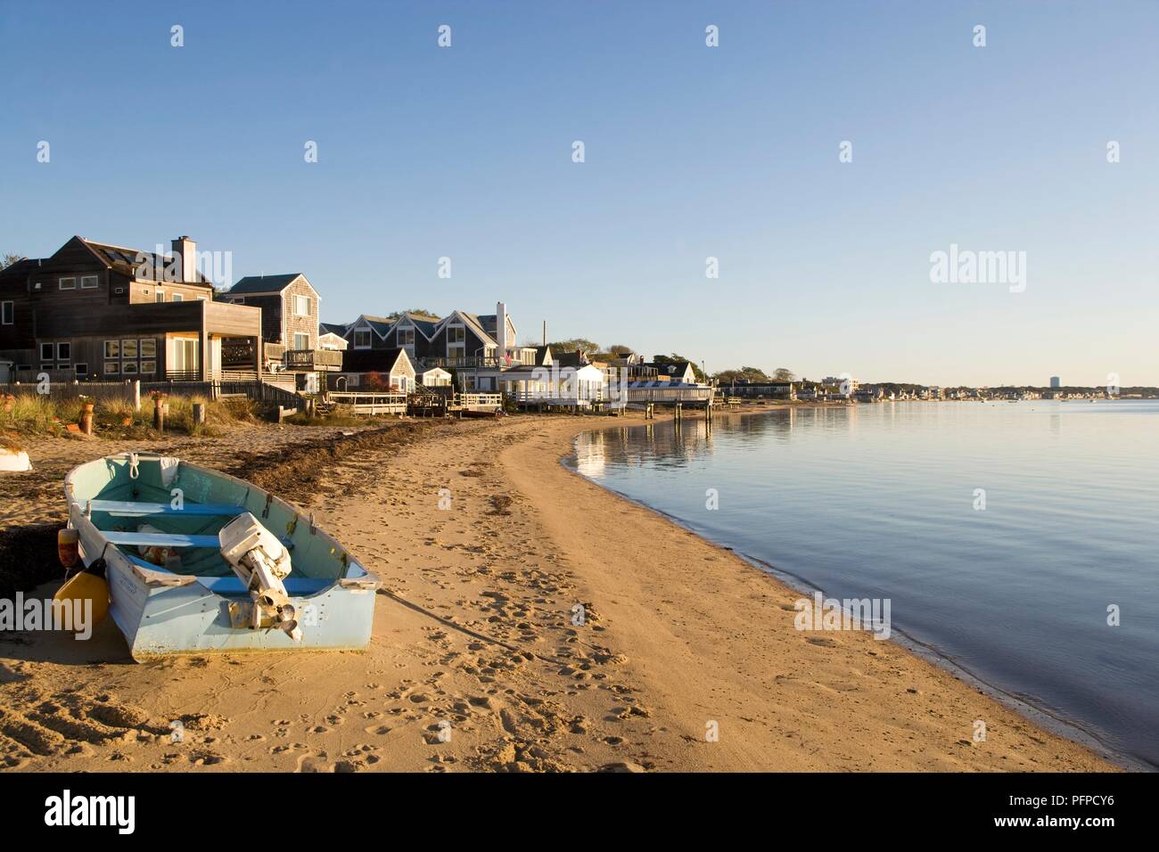 USA, Massachusetts, Cape Cod, Provincetown, small fishing boat on beach lined with houses Stock Photo