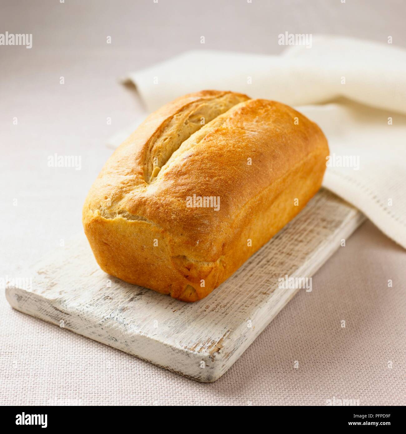 White loaf on wooden chopping board with napkin Stock Photo