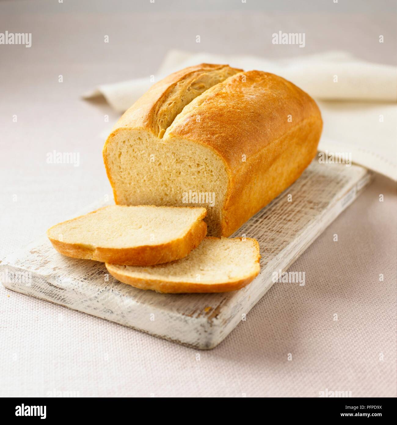 White loaf on wooden chopping board with napkin Stock Photo