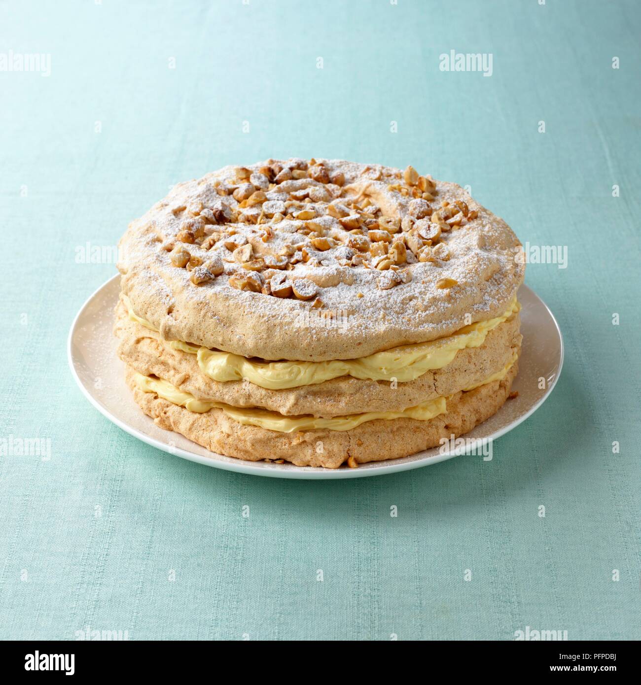 Whipped cream and hazelnut layered meringue served on white plate on blue tablecloth Stock Photo