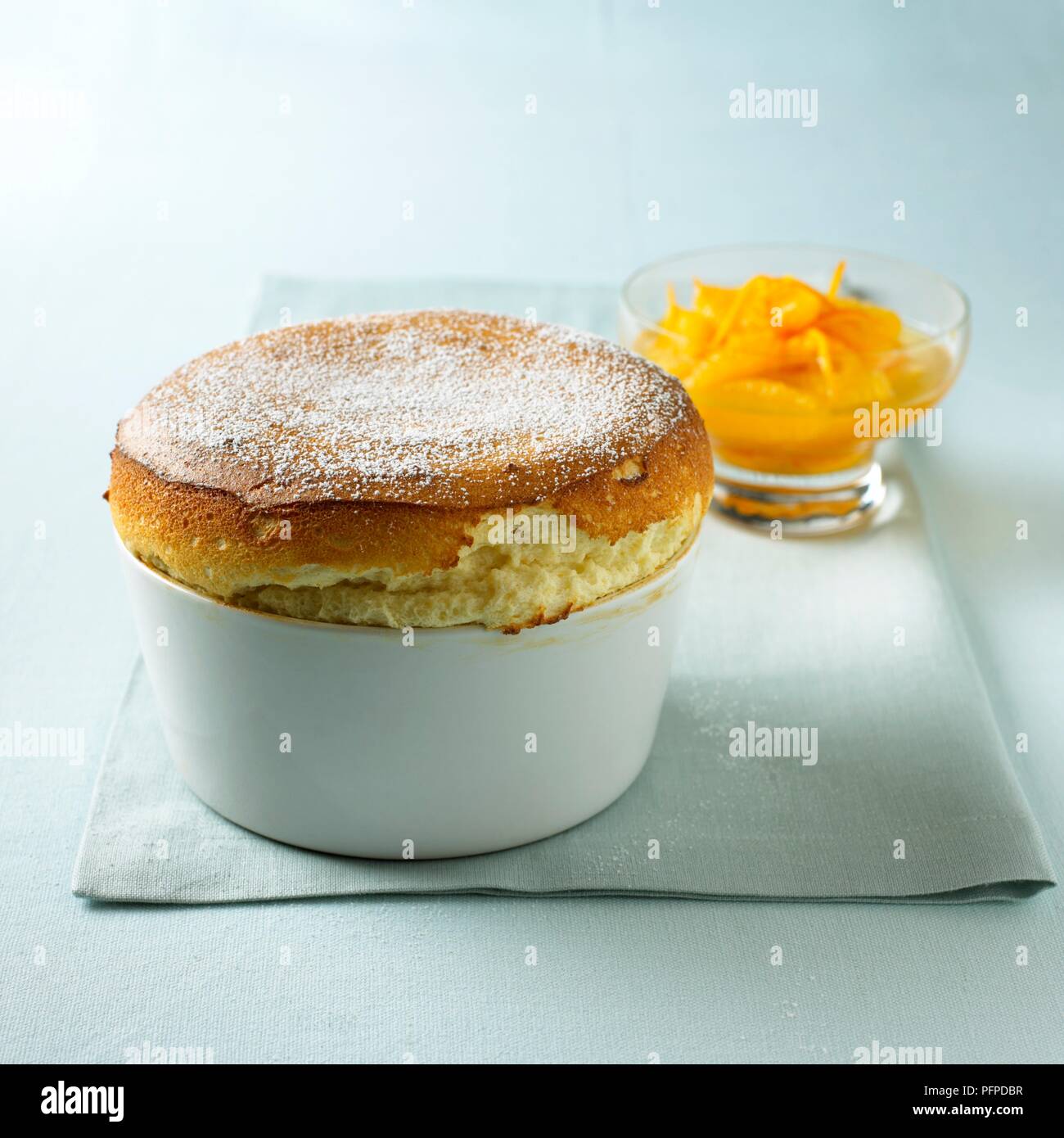 Grand marnier souffle in serving dish and sliced oranges in glass bowl