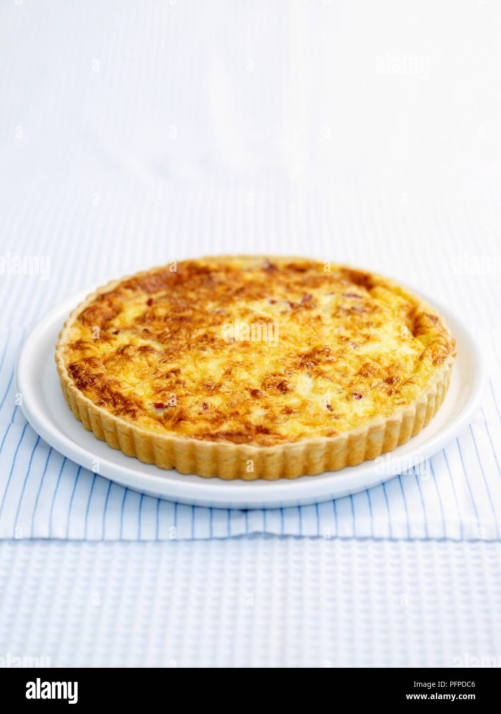 Quiche lorraine served on white plate and napkin Stock Photo