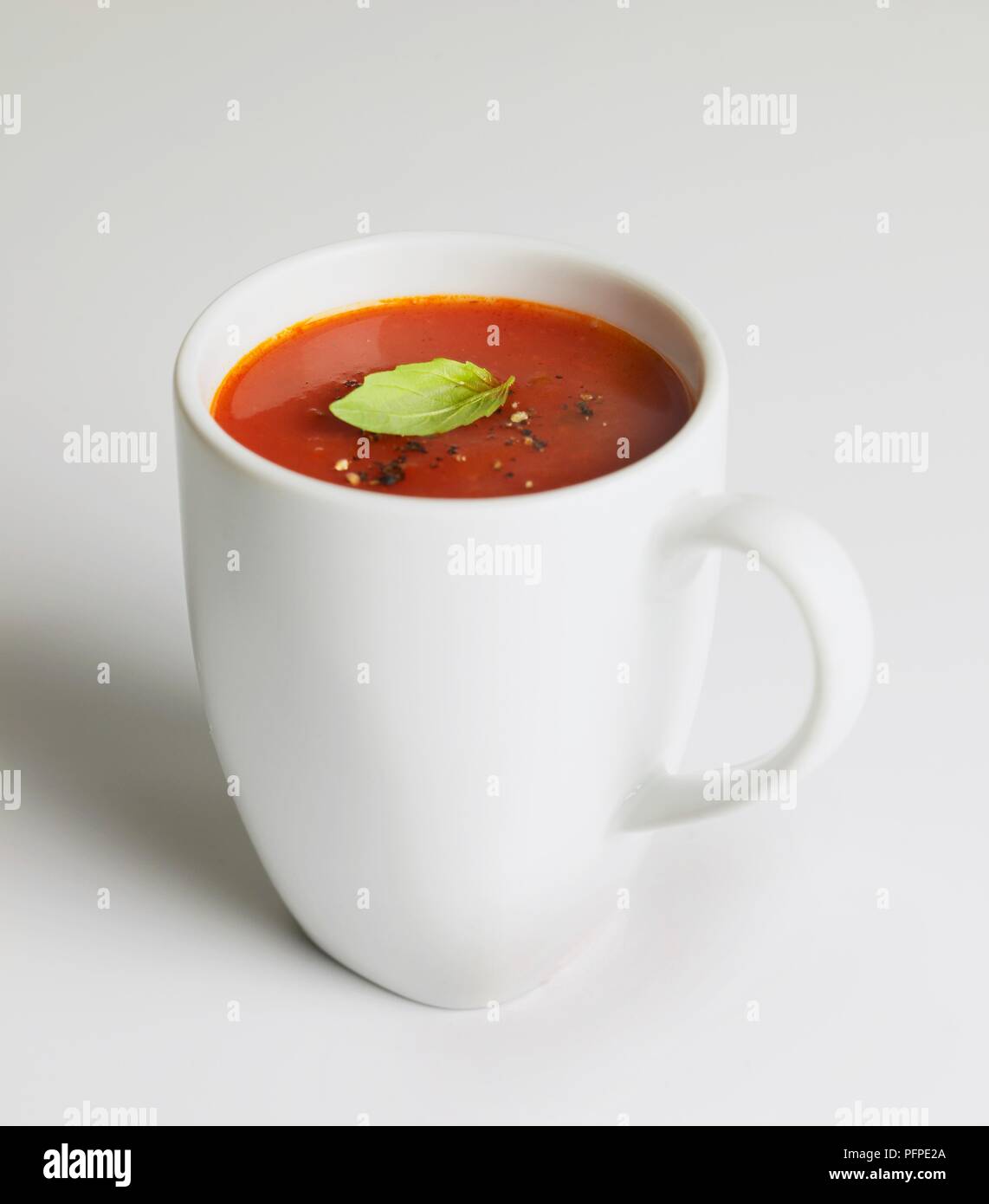 Tomato soup in mug, with crushed pepper and mint leaf Stock Photo
