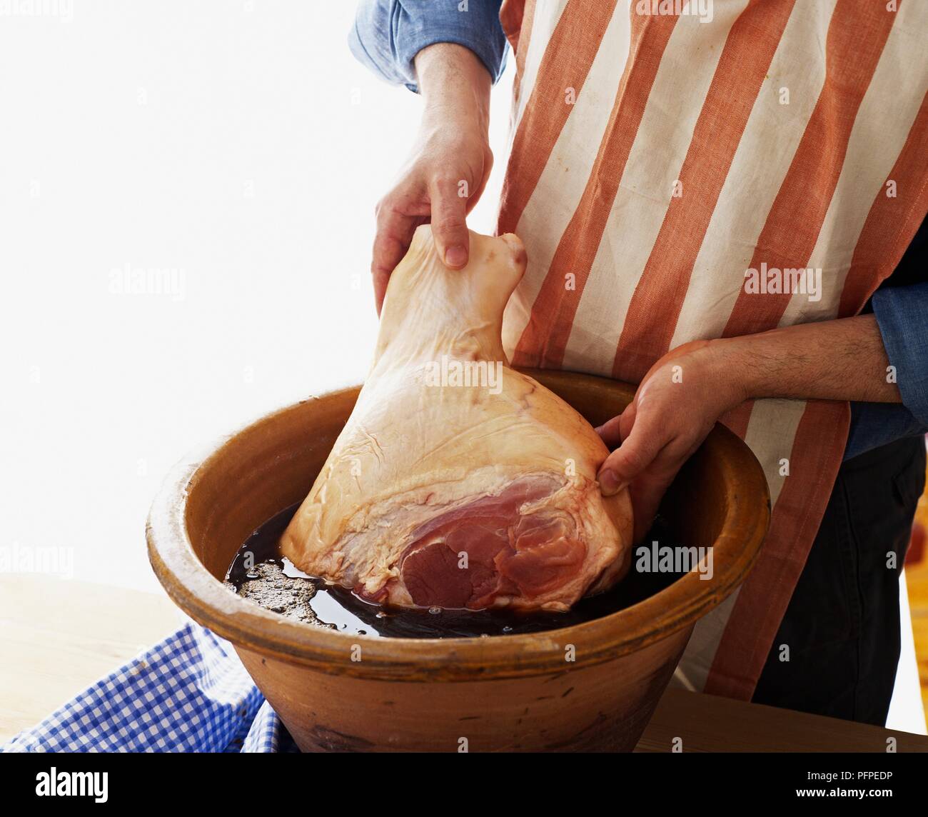 Putting ham in earthenware crock of brine curing during curing process