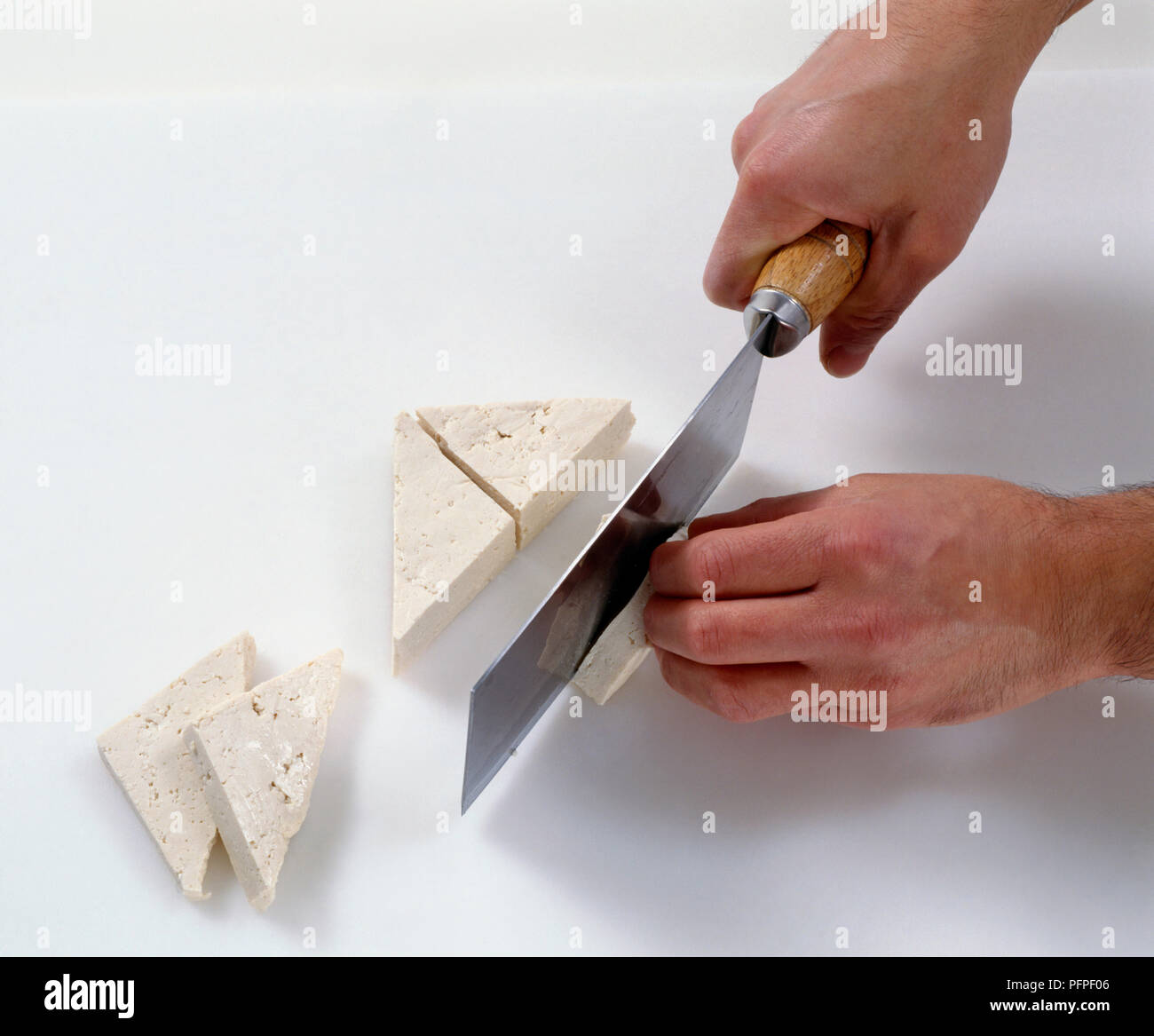Cutting tofu into triangle shapes, using a cleaver Stock Photo - Alamy