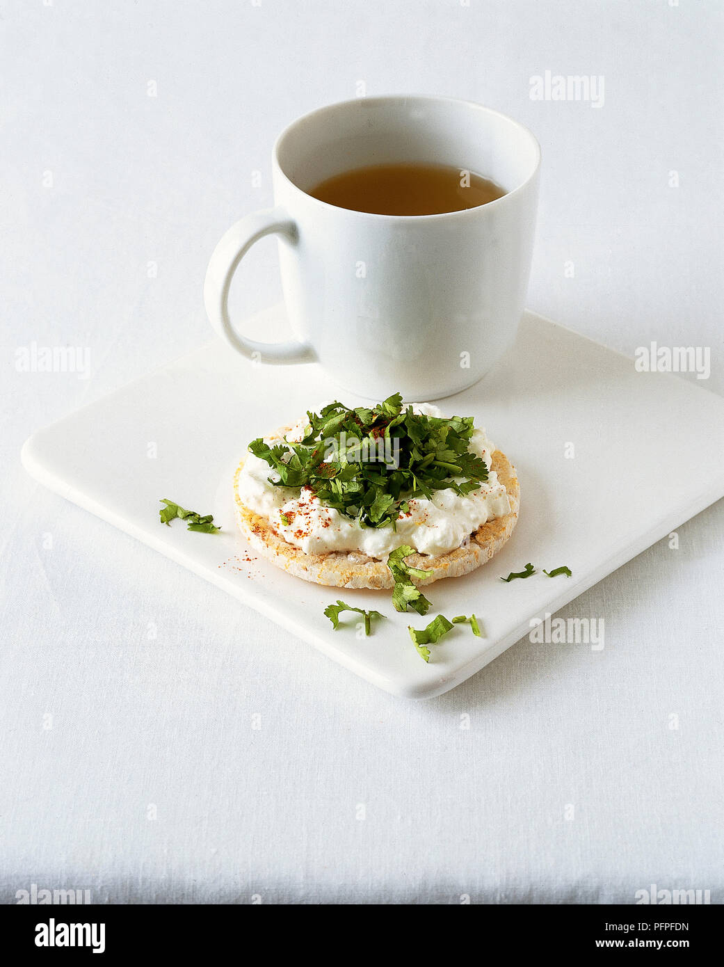 Mug of clear soup served with rice cake, topped with cottage cheese and chopped fresh coriander Stock Photo