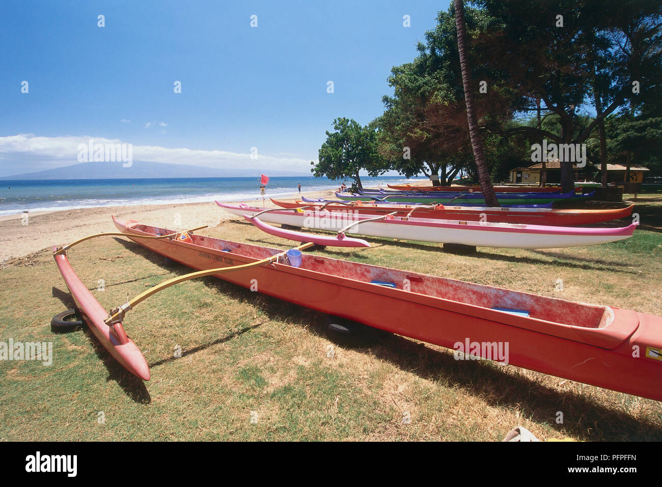 USA, Hawaii Islands, West Maui, Keka'a Beach, red and white Hawaiian canoes on grass overlooking Pacific Ocean Stock Photo