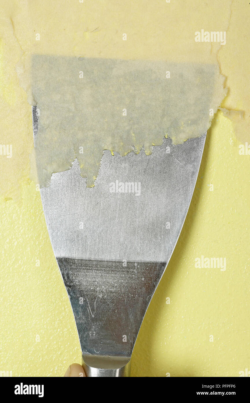 Using scraper to remove yellow wallpaper, close up Stock Photo - Alamy