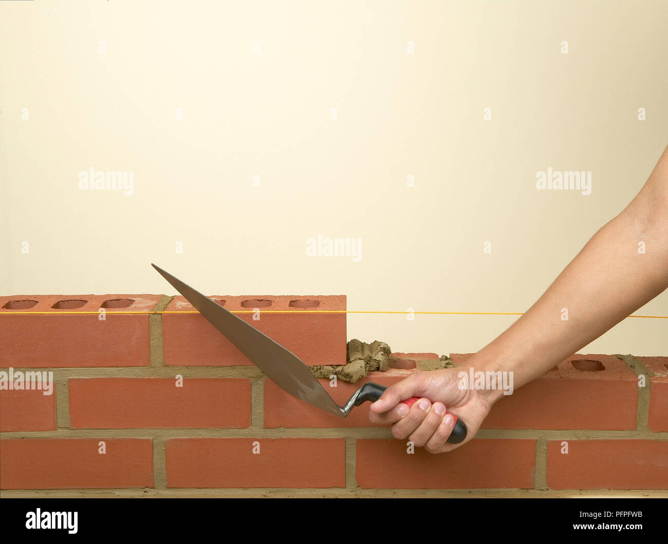 Building a brick wall, removing excess mortar with a trowel Stock Photo