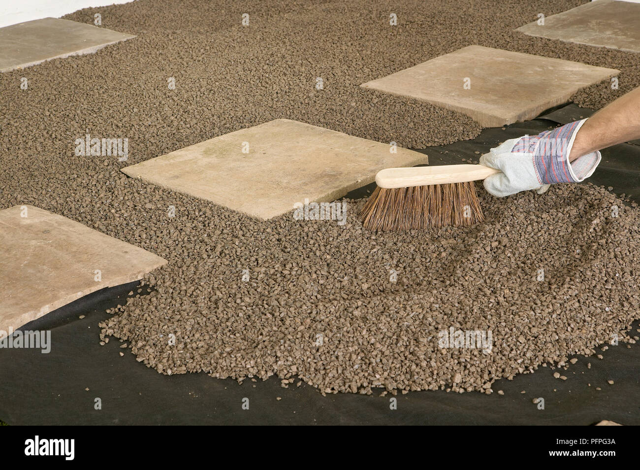 Brushing gravel around stepping stones, close-up Stock Photo