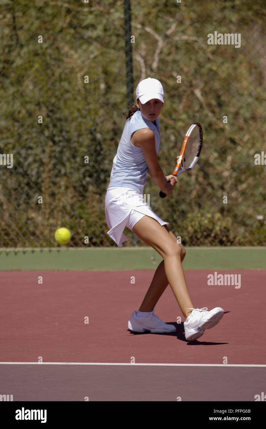 Young woman preparing to hit ball using two-handed backhand shot Stock Photo