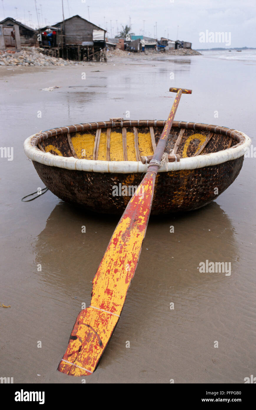 Vietnam, Long Hai, round boat and paddle on wet sand in coastal township Stock Photo