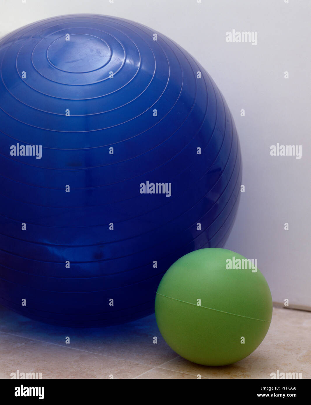 A large blue ball and a smaller green ball side by side Stock Photo