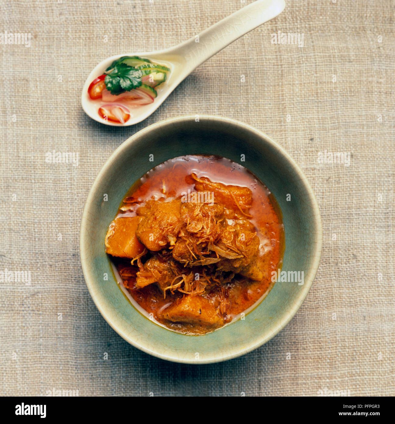 Geng gari fak tong, Thai pumpkin curry garnished with deep-fried shallots, cucumber relish in spoon Stock Photo