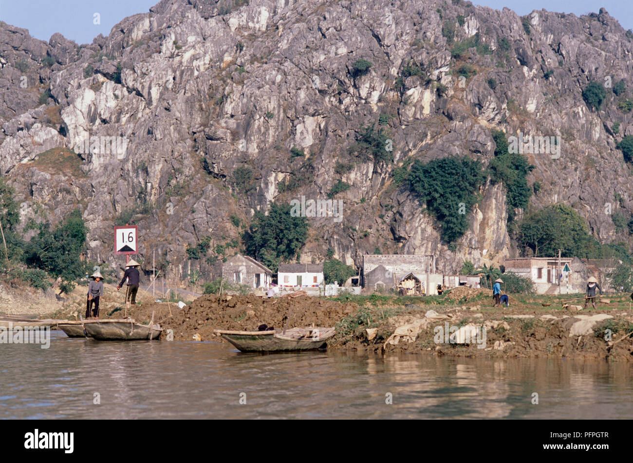 Vietnam, Kenh Ga, people working on riverbank and paddy fields at foot of mountain Stock Photo