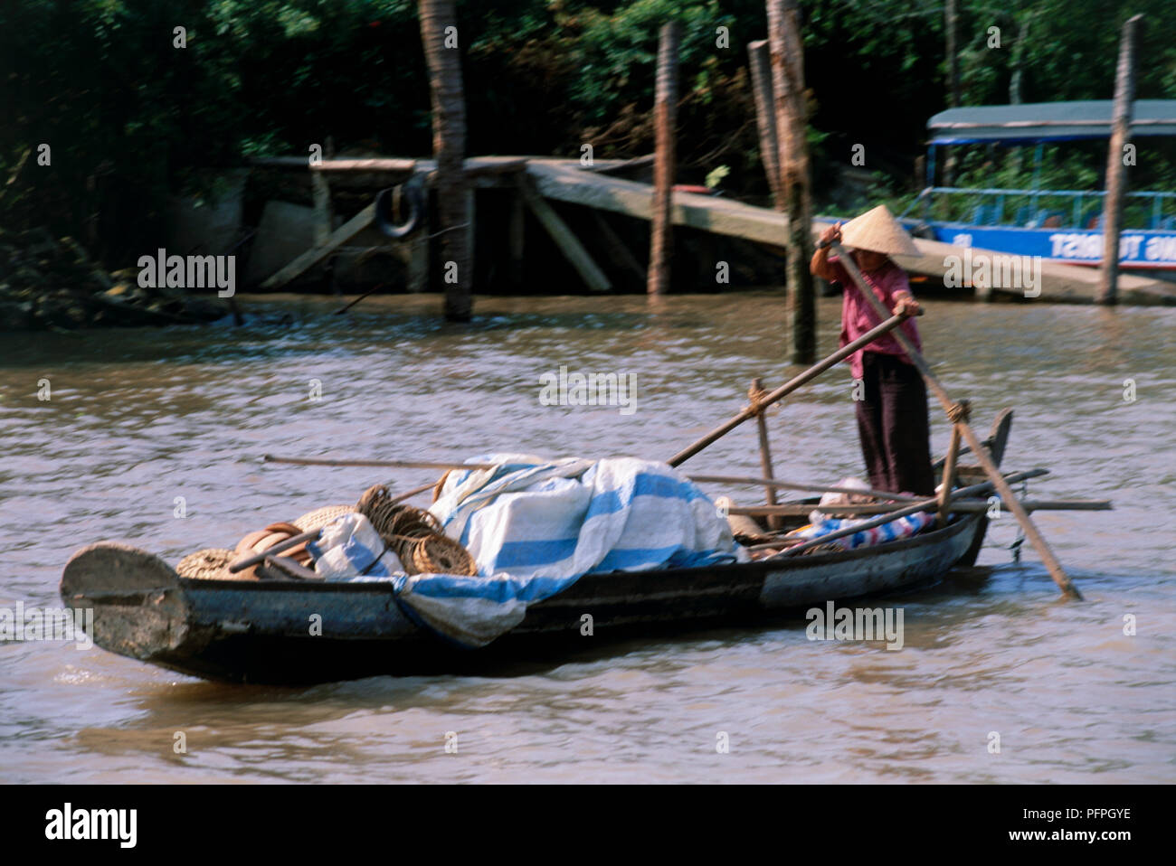 Vietnam, Mekong Delta, woman rowing sampan boat on river with long oars Stock Photo