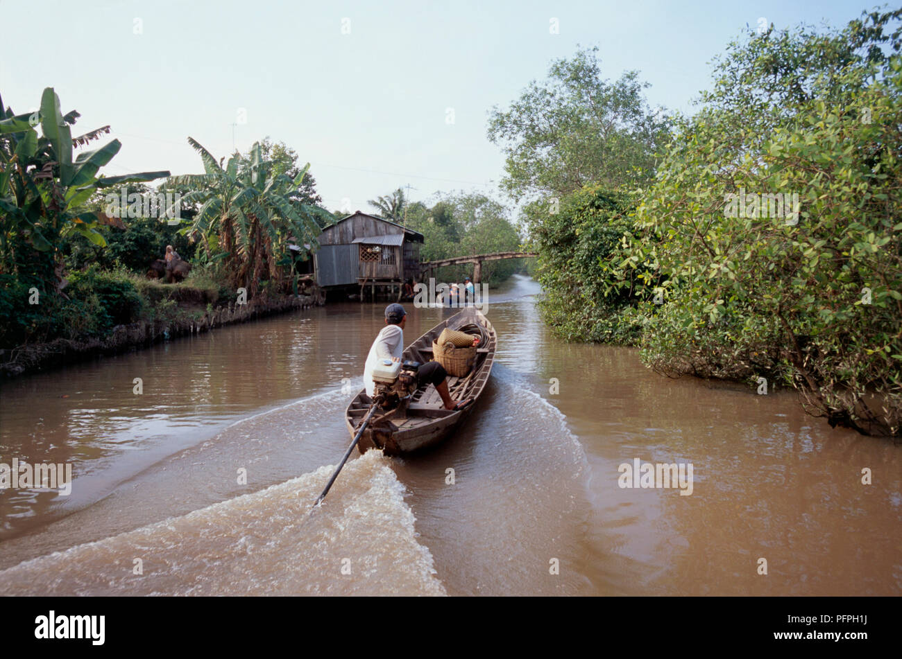Vietnam, Mekong Delta, man steering boat on muddy canal Stock Photo