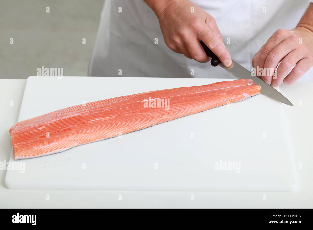 Skinning a salmon fillet, making a cut between the flesh and skin at
