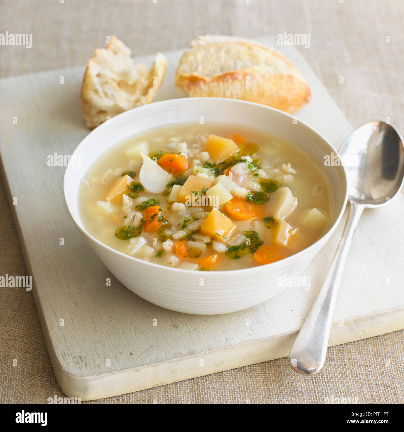 Bowl of leek, barley and root vegetable broth with olive oil, served with some white bread Stock Photo