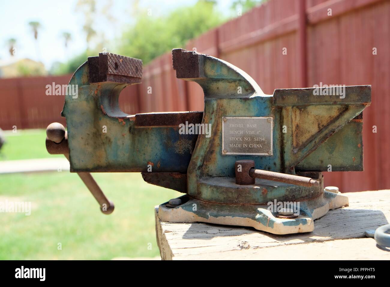 Rusted swivel base 4-inch vise bolted on a wooden table. Stock Photo