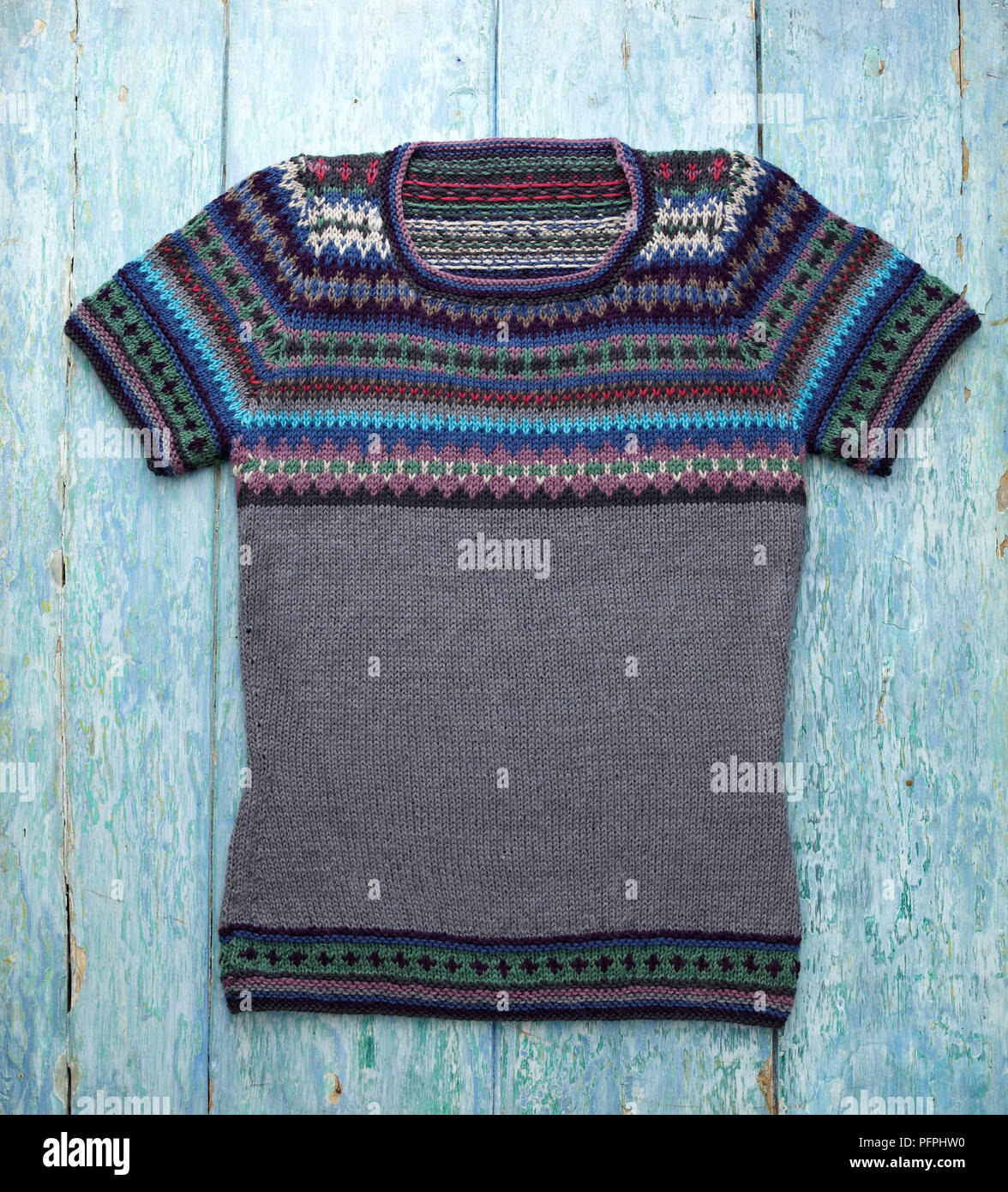 Fair-isle knitted yoke top on blue wood background, close-up Stock Photo