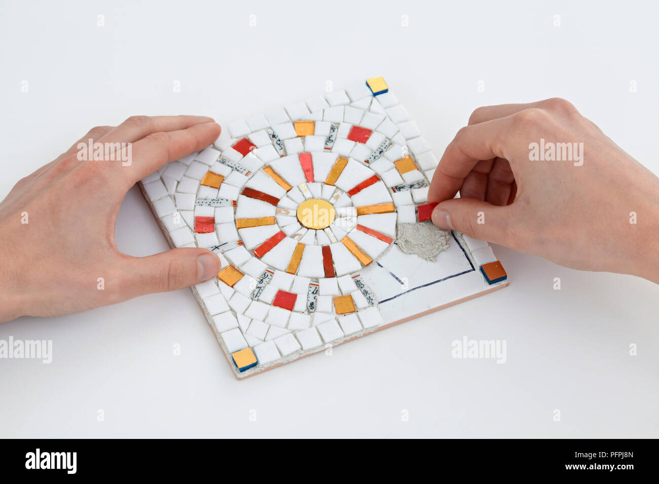 Carefully positioning mosaic pieces in cement-based adhesive on tile ...