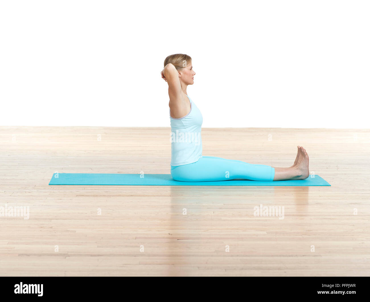 Woman practising spine twist Pilates mat exercise, side view Stock