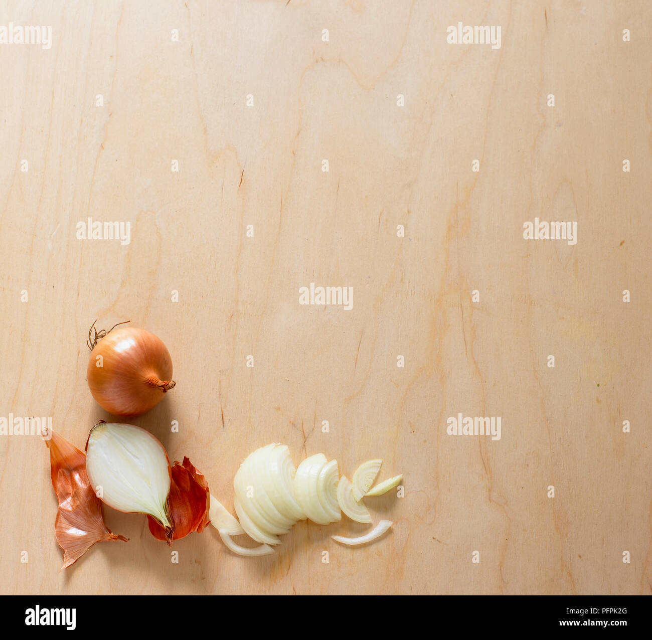Whole, halved, peeled and sliced onions on wooden surface Stock Photo