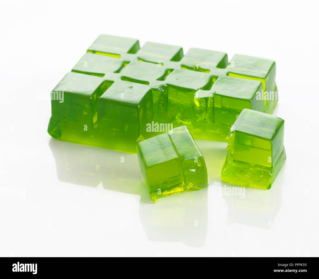 Block of set green jelly (made using ice cube tray), with some pieces broken off Stock Photo