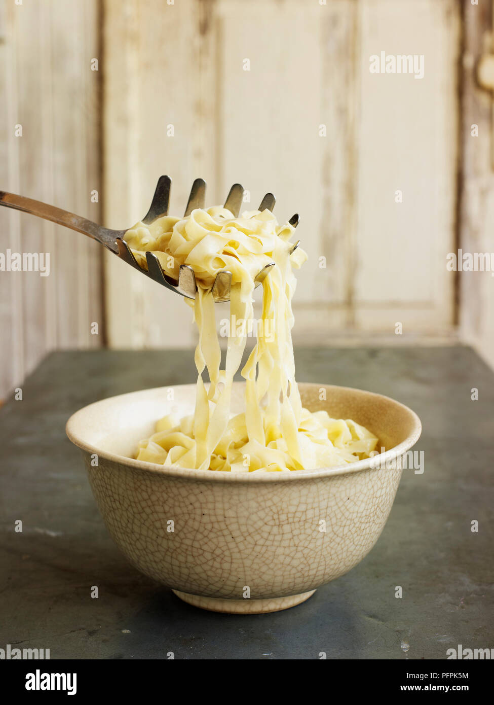 Using pasta scoop to lift tagliatelle pasta out of bowl Stock Photo Alamy