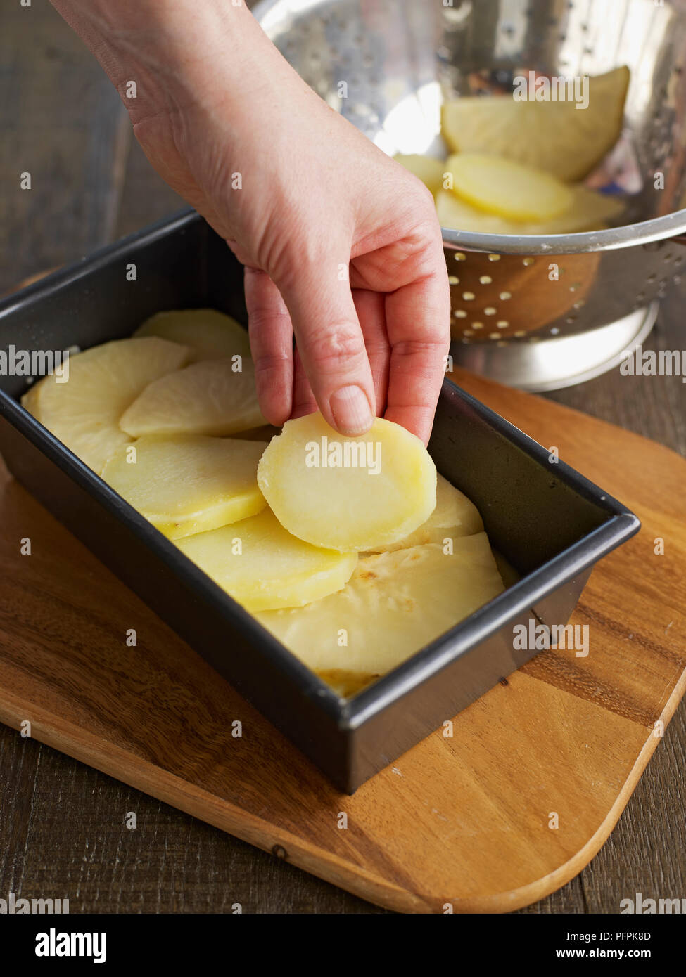 Layering potato and celeriac slices in loaf tin (making potato and celeriac gratin) Stock Photo