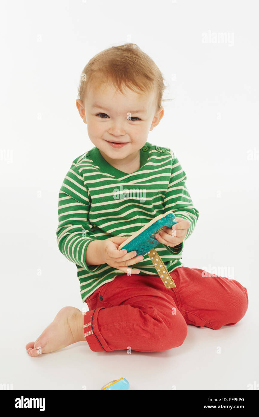 Little boy in green stripey top kneeling (Model age - 22 months) Stock Photo