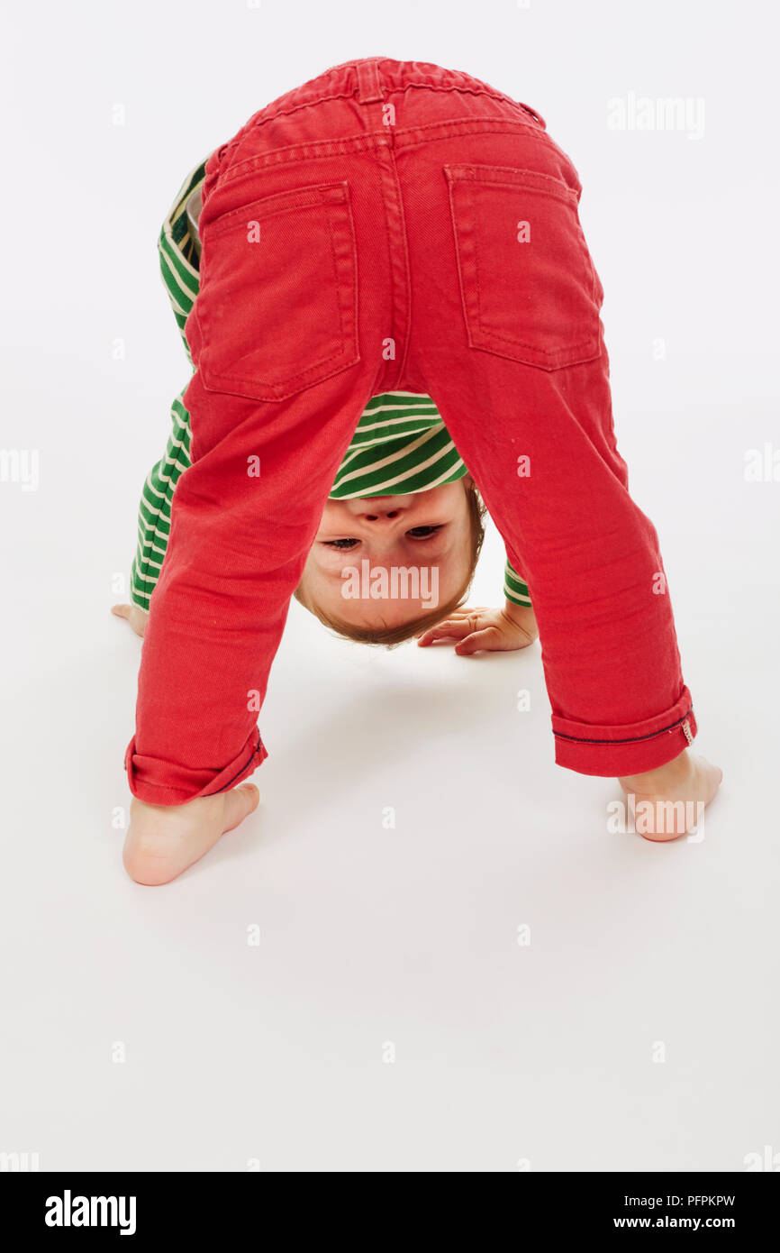 Little boy in green stripey top bending over (Model age - 22 months) Stock Photo
